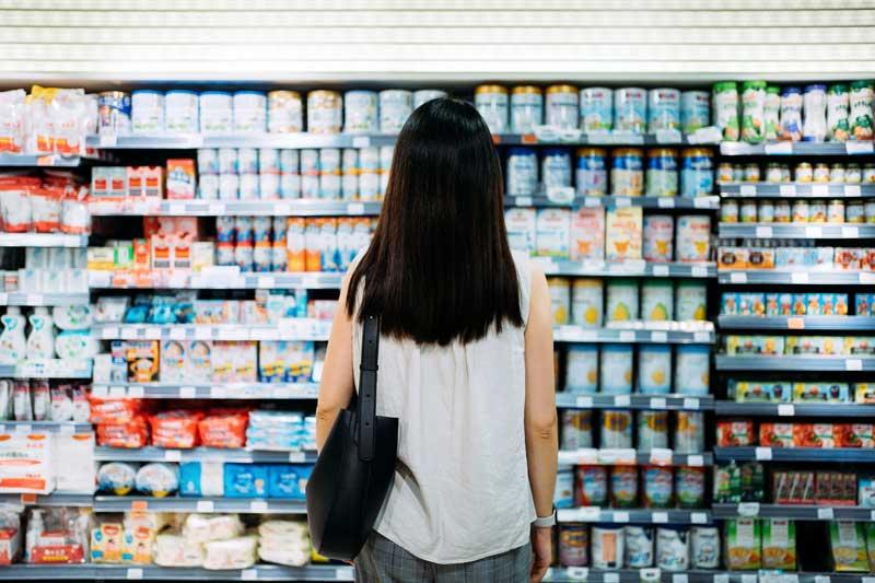 一个女人看着杂货店货架上的酸奶